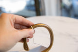Hand holding collector's bronze cuff, highlighting etched pattern and rich patina.