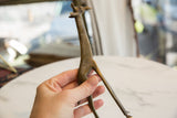 Vintage bronze giraffe sculpture held in hand showing its detailed form and textured patina.