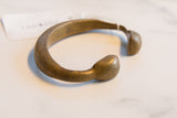 Angled profile of the antique African bronze cuff highlighting its curved shape and patina.