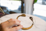 Hand holding an antique bronze snake cuff, showing its open form and stylized ends.