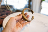Antique African bronze snake cuff held in hand, showing its curved form and finish.