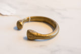 Antique bronze snake cuff bracelet showing its open C-shape and bulbous ends.