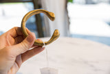 Antique bronze snake cuff bracelet held up, displaying its open form and aged patina.