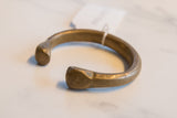 The hand-worked surface and faceted terminal of an antique bronze snake cuff.