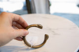 Antique African bronze snake cuff held to display its curved shape and aged, textured surface.
