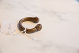 Antique African copper alloy cuff bracelet displayed with its handwritten paper inventory tag.