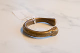 Angled view of the handcrafted African bronze cuff showing its open shape and aged patina.