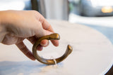Hand holding an antique bronze snake cuff, detailing its stylized head and aged patina.