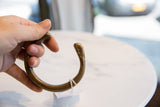 Antique bronze snake cuff held in hand, showing its substantial form and patina.