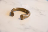 Angled view of a solid, hand-forged antique African bronze cuff with an aged patina.