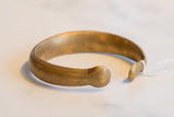 The smooth, curved shape and flared ends of an antique African bronze cuff bracelet.
