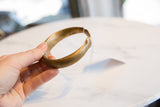 Side profile of an antique bronze snake cuff showing its smooth, rounded shape and patina.