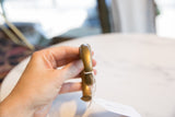 Angled profile of the antique bronze cuff bracelet showing its smooth, aged surface.