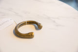 Antique African bronze cuff bracelet showing its open form and smooth, rounded ends from an angle.