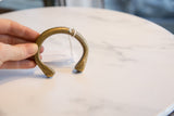 A hand holds the antique bronze cuff bracelet, highlighting its handmade form and patina.