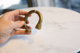 Antique African bronze cuff shown in hand, displaying its open C-shape and stylized snake head.