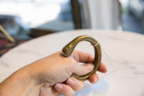 Antique bronze snake cuff bracelet held, showing the smooth, aged patina and scale.