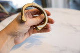 Holding the antique bronze snake cuff to show its substantial, curved form and smooth patina.