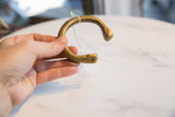 The substantial form of an antique African bronze snake cuff shown in hand.