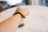 Antique African bronze snake cuff bracelet modeled on a wrist to show scale and fit.