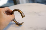 A hand holds the antique bronze cuff, displaying its open form and warm patina.
