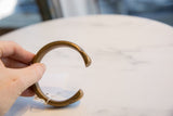 A hand holding the antique bronze snake cuff bracelet to show its scale and warm patina.