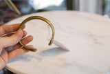 The smooth, curved form of the antique bronze cuff with aged patina.