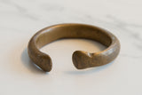 Profile view of the antique bronze cuff bracelet highlighting its thick form and aged patina.