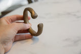 Antique bronze cuff bracelet held to show its substantial scale and open C-shape.