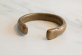 Side profile of the antique bronze snake cuff, highlighting its worn patina and open shape.