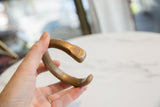 Antique bronze snake cuff bracelet held to show its profile and worn patina.