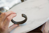 Antique African copper alloy bracelet held in hand to show its scale and dark patina.