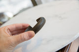 Antique African bracelet held to show its thick, curved form and dark, textured patina.