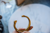 Antique African bronze cuff held in hand, showing its warm golden patina and shape.