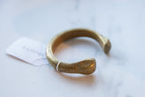 Hand-stamped '33' mark on the aged golden patina of an antique bronze cuff.