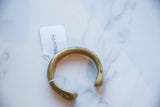 The solid C-shape and aged golden patina of an antique African cuff.