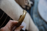 The warm golden patina and handcrafted surface of the antique bronze bracelet.