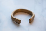 Antique copper alloy cuff bracelet showing its thick, open form and aged patina.