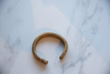 The open C-shape and aged patina of a collectible African copper alloy cuff.