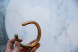 Antique African copper alloy cuff held to show its open C-shape and aged patina.