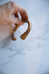 The smooth, worn surface and rounded end of the antique African copper cuff.