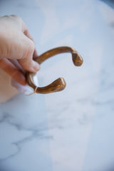 A hand holding the antique copper alloy snake cuff, showing its size and shape.