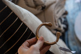 A hand holding the antique copper snake cuff to show its scale and warm patina.