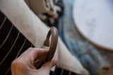Angled view of the antique copper alloy cuff's handmade texture and curved form.