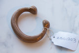 Antique African copper snake cuff showing its aged patina and paper tag.