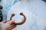 Antique copper snake cuff bracelet held to display its open form and sculpted heads.