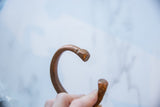 Stylized snake ends and curved opening of the antique African copper cuff bracelet.