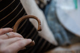 A hand holding the antique copper cuff, showing its etched patterns and flared end.