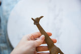 Hand holding vintage African bronze giraffe, revealing textured head and neck.