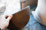 Antique African wooden bowl held by hand, revealing unique zig-zag patterns and rich wood grain.